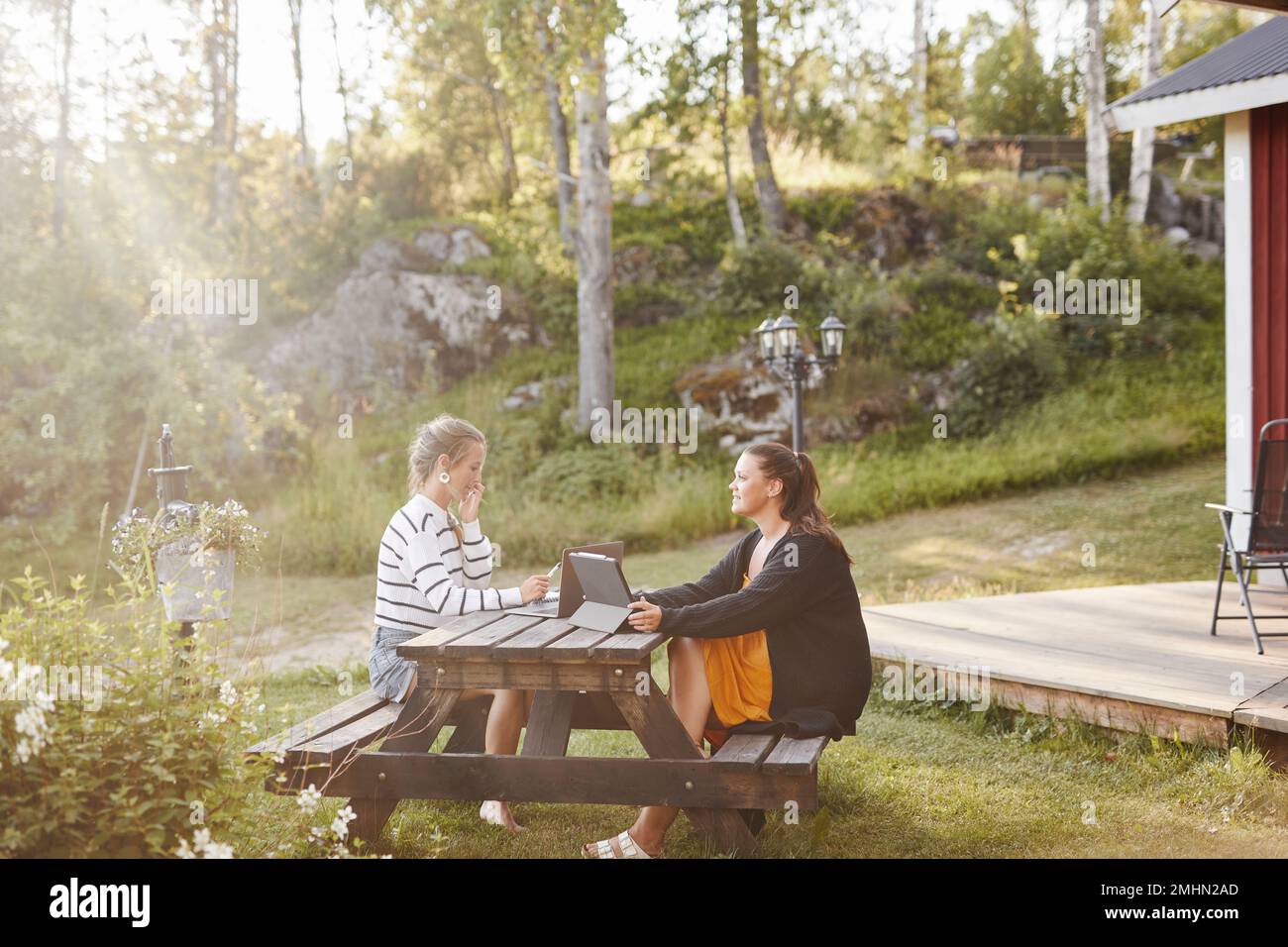 Female friends sitting on picnic bench Stock Photo
