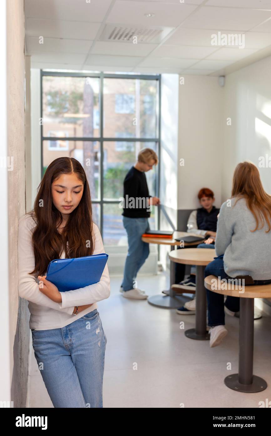 Group of friends and lone girl on school corridor Stock Photo