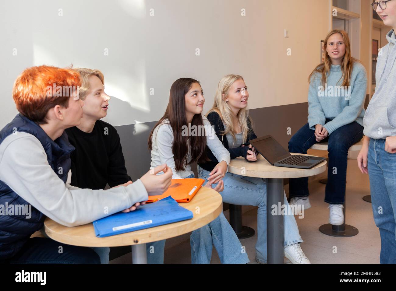 Teenagers sitting and talking on school corridor Stock Photo