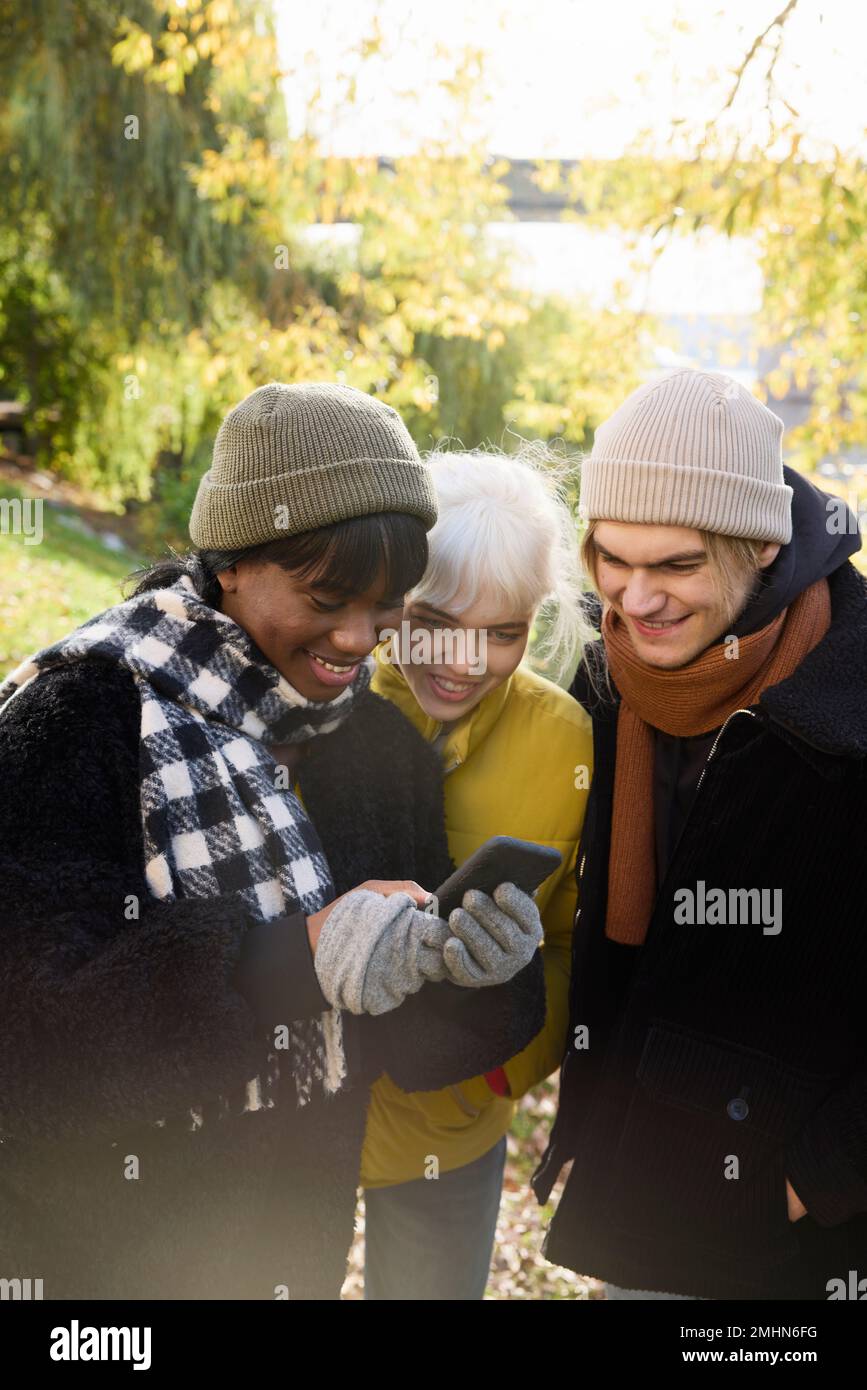 Smiling young friends looking at cell phone Stock Photo