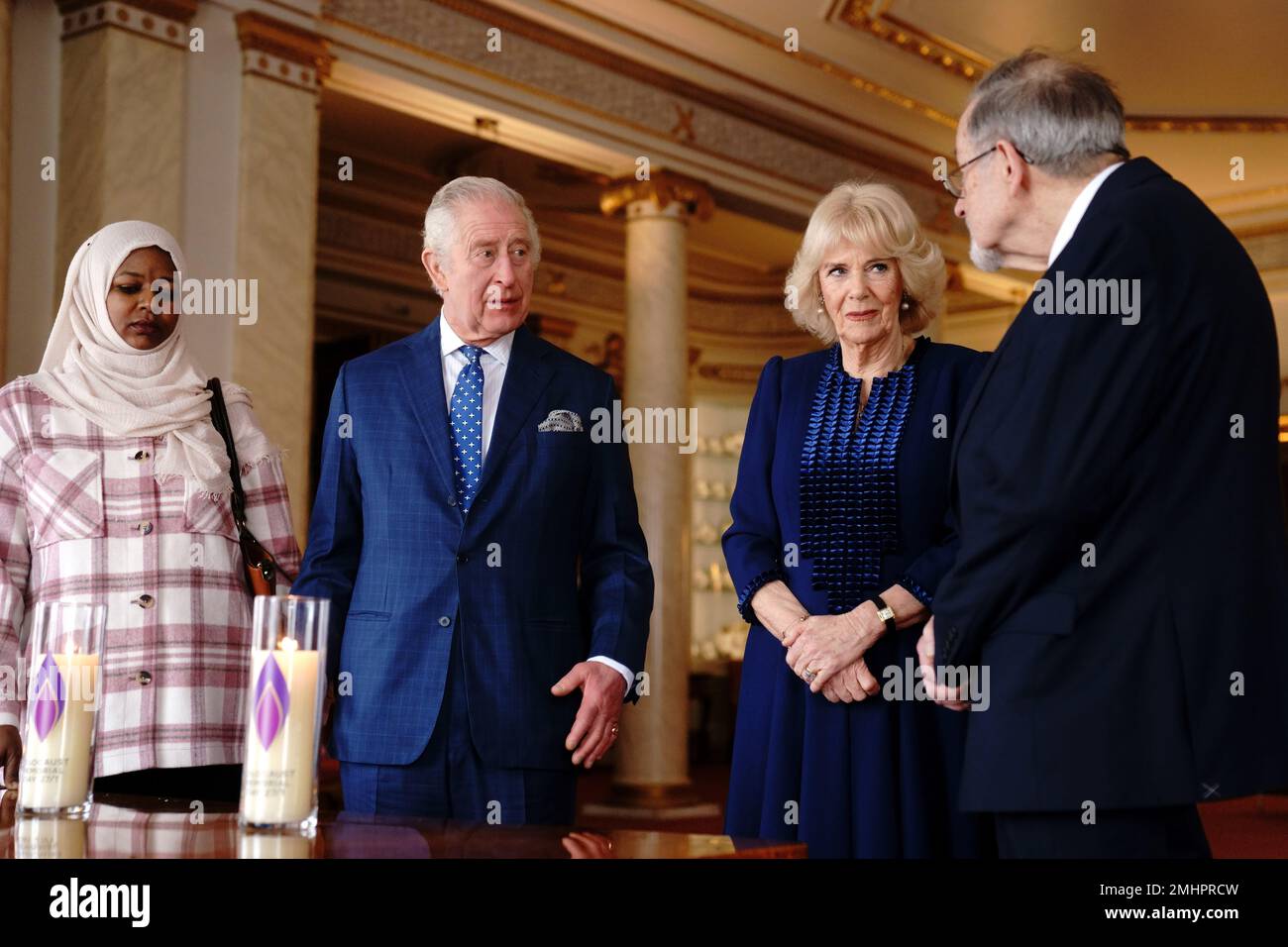 King Charles III and the Queen Consort light a candle at Buckingham Palace, London, to mark Holocaust Memorial Day, alongside Amouna Adam (left), a survivor of the Darfur genocide, and Holocaust survivor Dr Martin Stern (right). Picture date: Friday January 27, 2023. Stock Photo