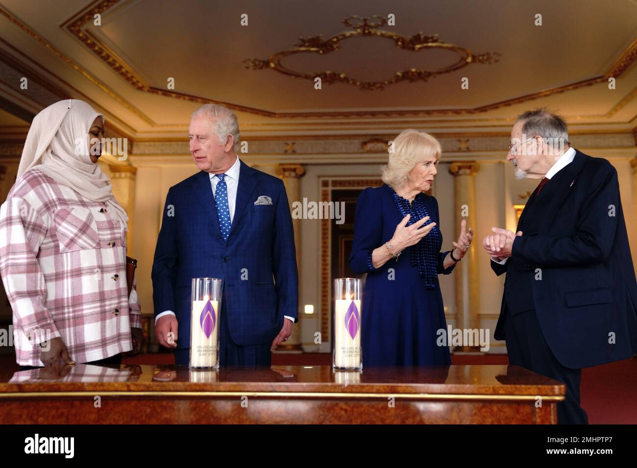 King Charles III and the Queen Consort talk Amouna Adamlight, a survivor of the Darfur genocide, and Holocaust survivor Dr Martin Stern, after lighting a candle to mark Holocaust Memorial Day at Buckingham Palace, London. Picture date: Friday January 27, 2023. Stock Photo