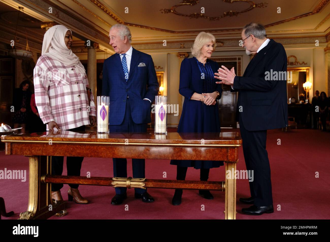 King Charles III and the Queen Consort talk with Amouna Adamlight (left), a survivor of the Darfur genocide, and Holocaust survivor Dr Martin Stern (right), after lighting a candle to mark Holocaust Memorial Day at Buckingham Palace, London. Picture date: Friday January 27, 2023. Stock Photo