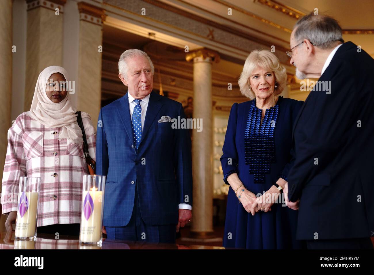 King Charles III and the Queen Consort talk with Amouna Adamlight (left), a survivor of the Darfur genocide, and Holocaust survivor Dr Martin Stern (right), after lighting a candle to mark Holocaust Memorial Day at Buckingham Palace, London. Picture date: Friday January 27, 2023. Stock Photo