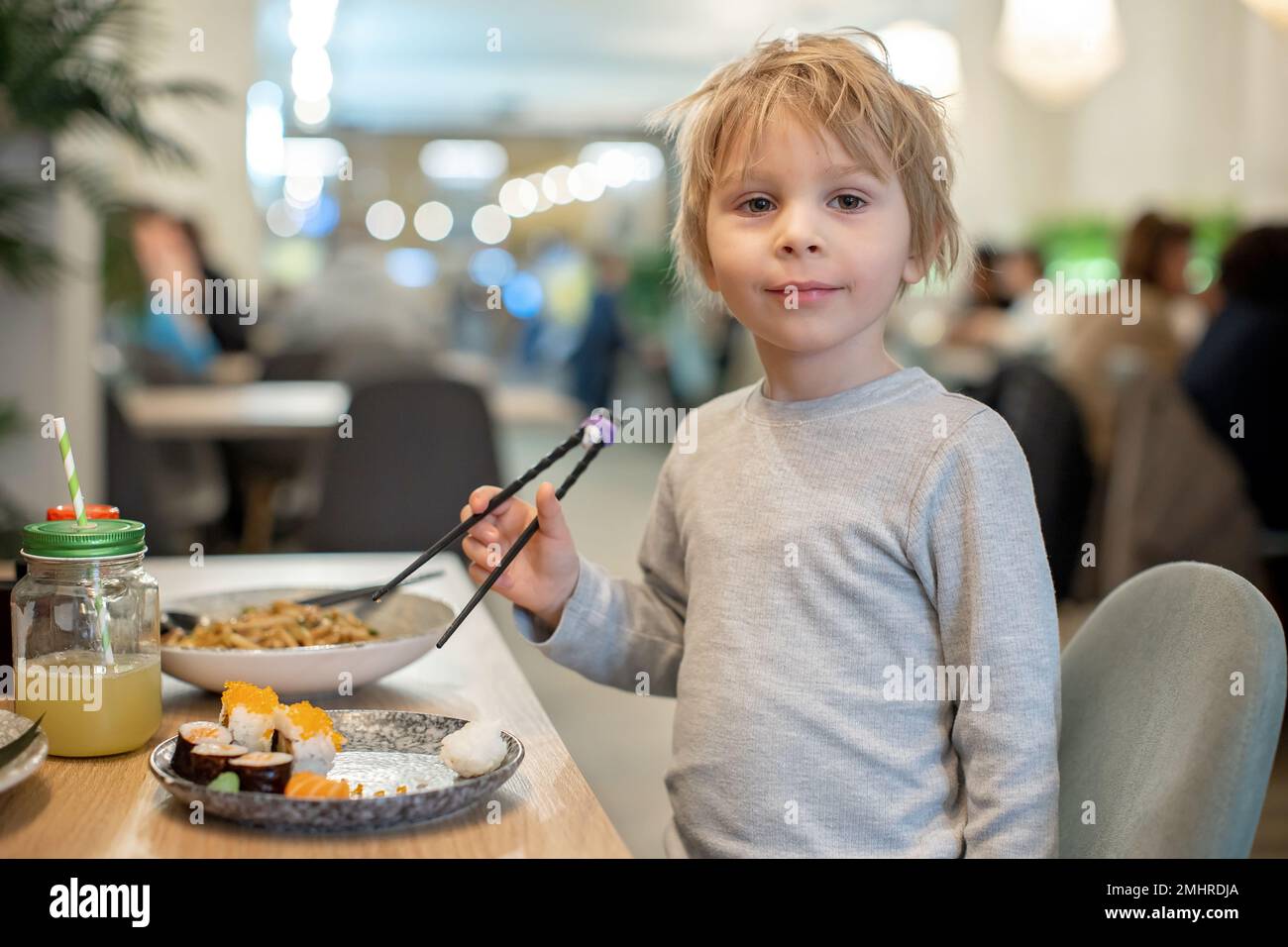 Child, eating japanese sushi and noodles with chopsticks in a restaurant, dinnertime Stock Photo