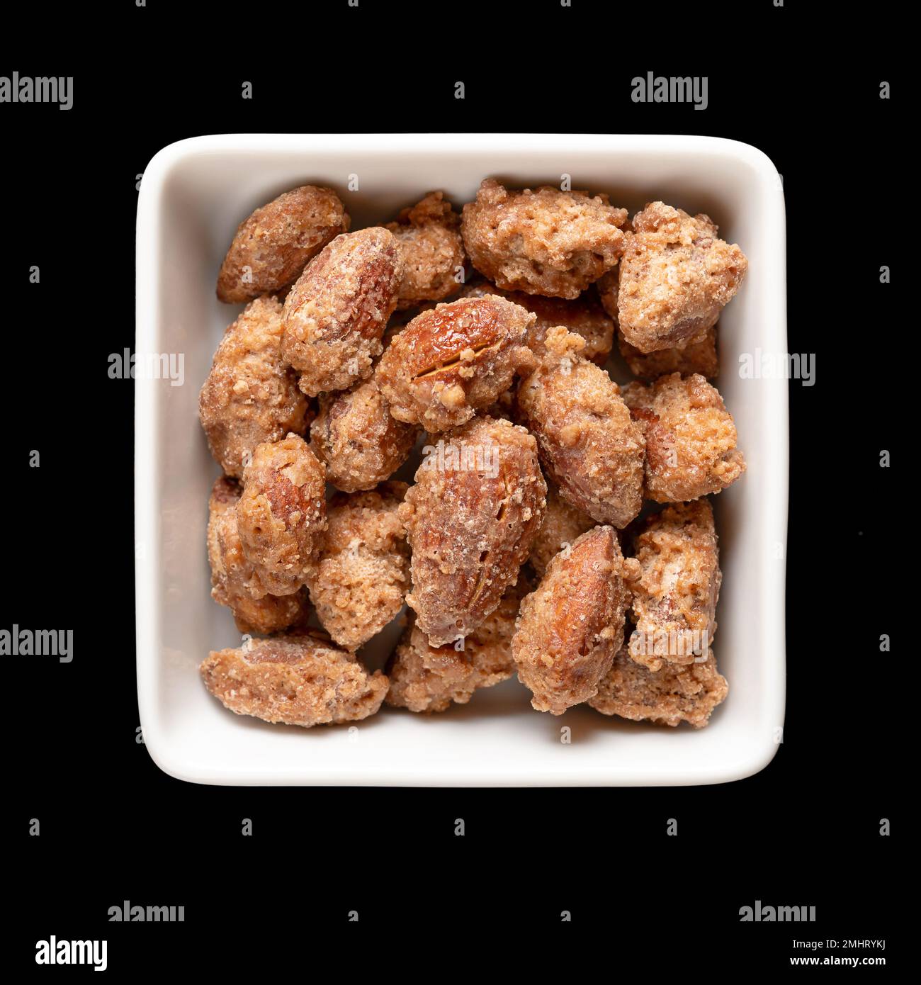 Candied almonds in a white square bowl. Homemade, in a special way cooked almonds, whole nuts coated in crunchy sugar. Sold at Christmas markets. Stock Photo