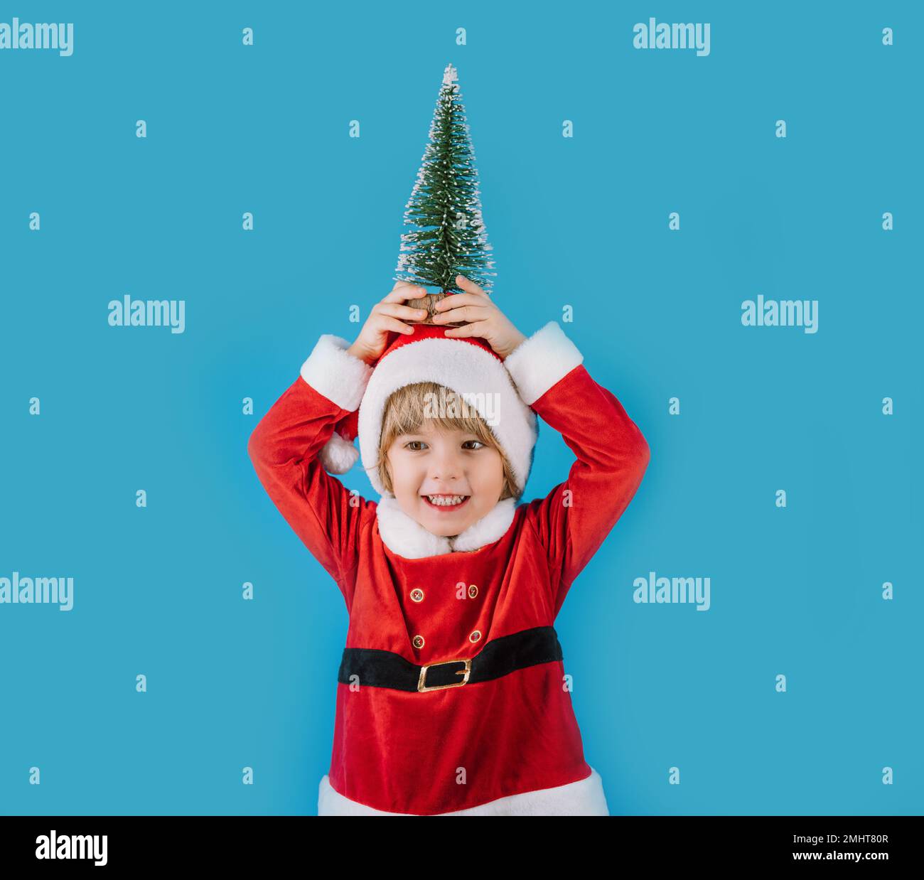 Friendly little Christmas boy in Santa Claus costume on blue background. Happy emotional child with artificial beard. High quality photo Stock Photo