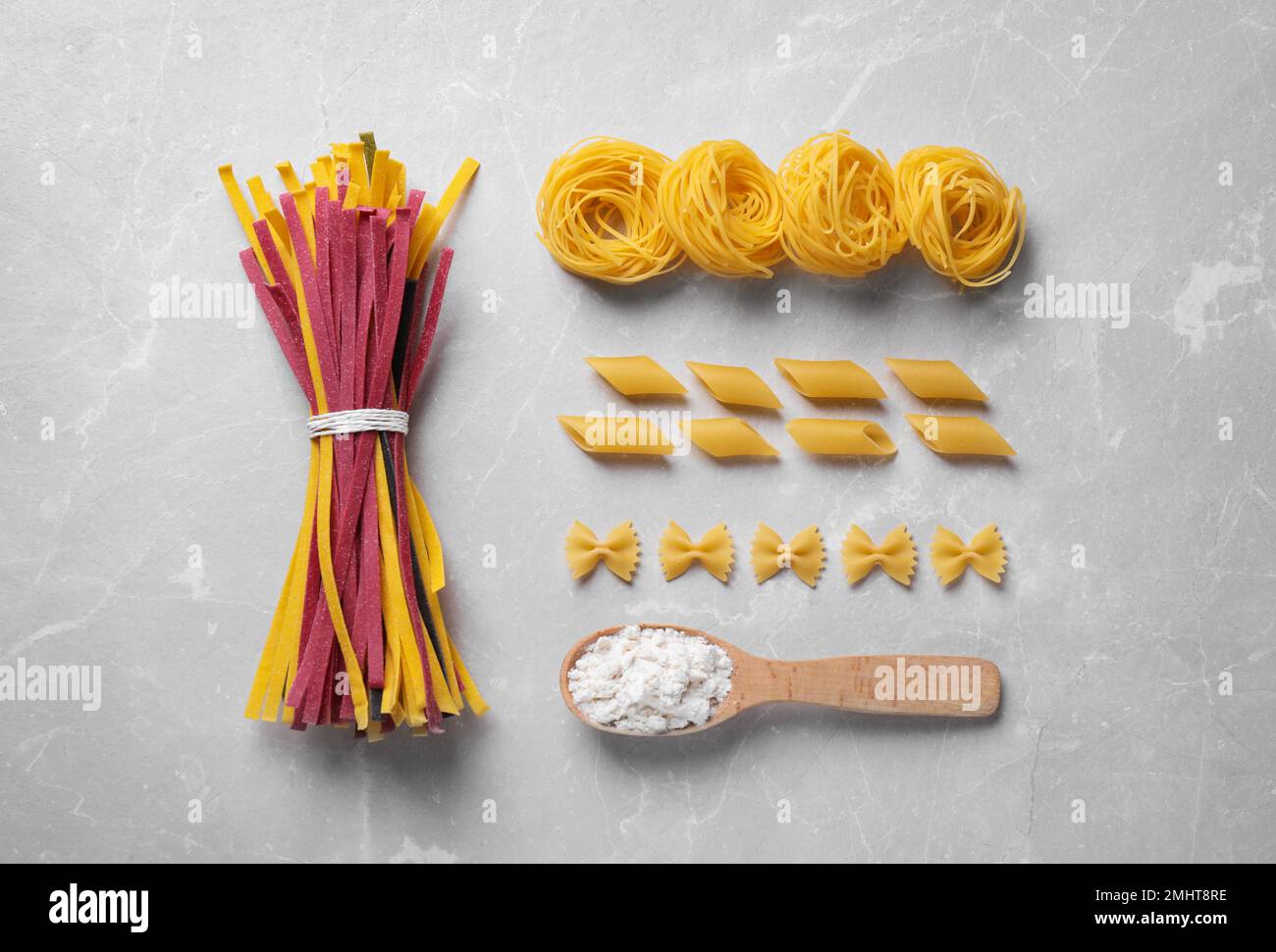 Flat lay composition with different types of pasta on light grey table ...