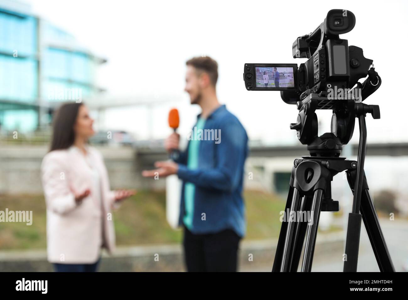 Young journalist interviewing businesswoman on city street, focus on camera display Stock Photo