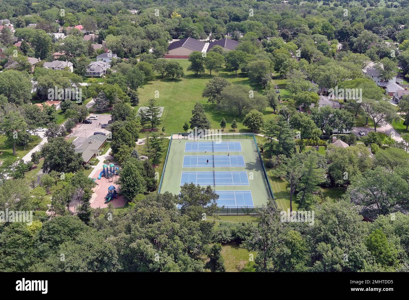 Aerial view of a park with a playground and tennis courts in a