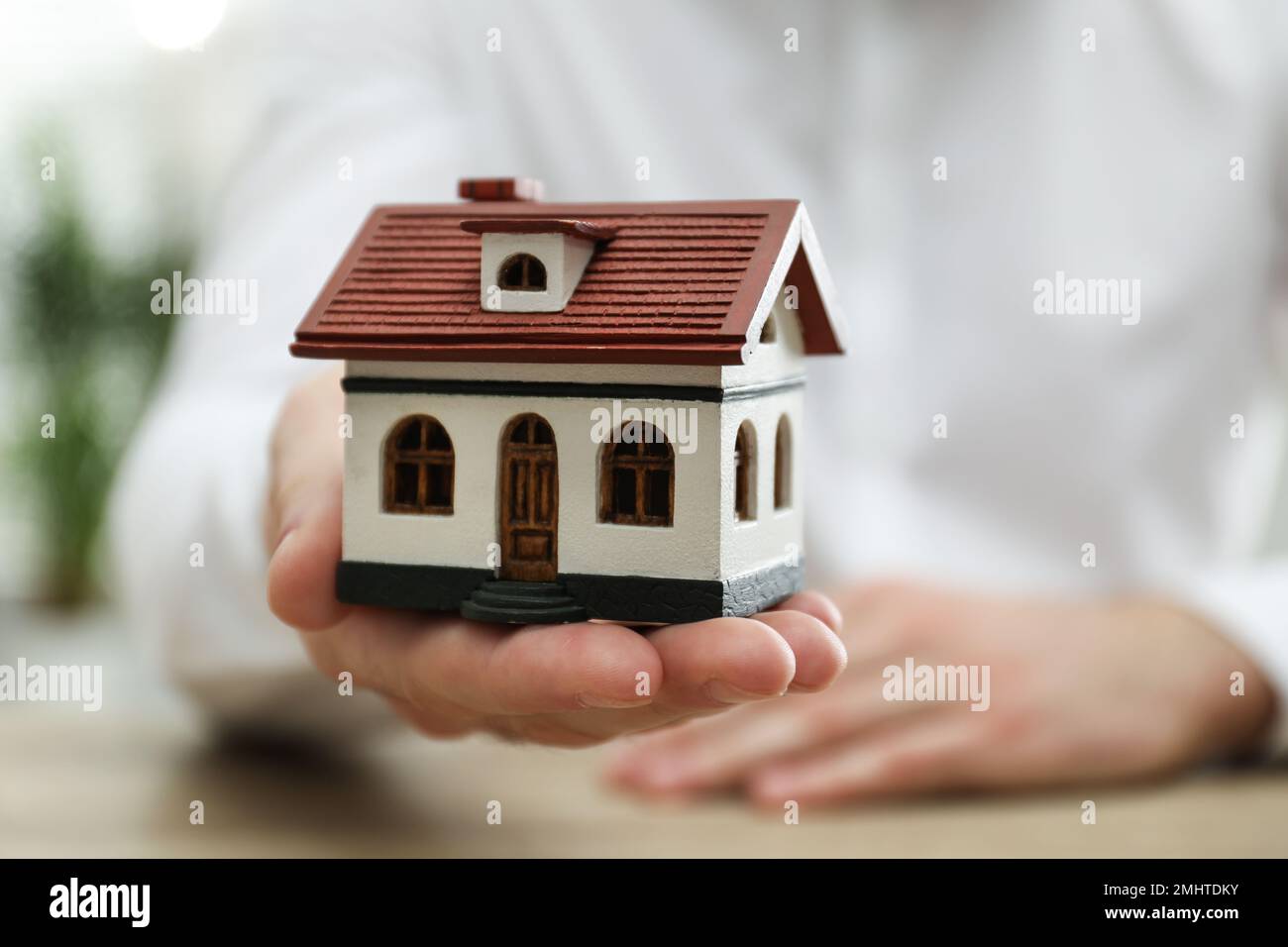 Real estate agent holding house model indoors, closeup Stock Photo - Alamy