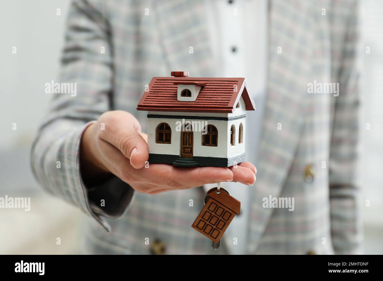 Real estate agent holding house model and key indoors, closeup Stock ...