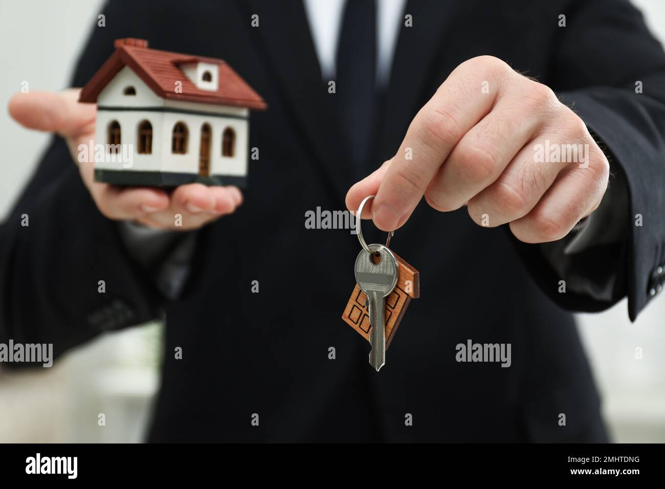 Real estate agent holding house model and key indoors, closeup Stock ...