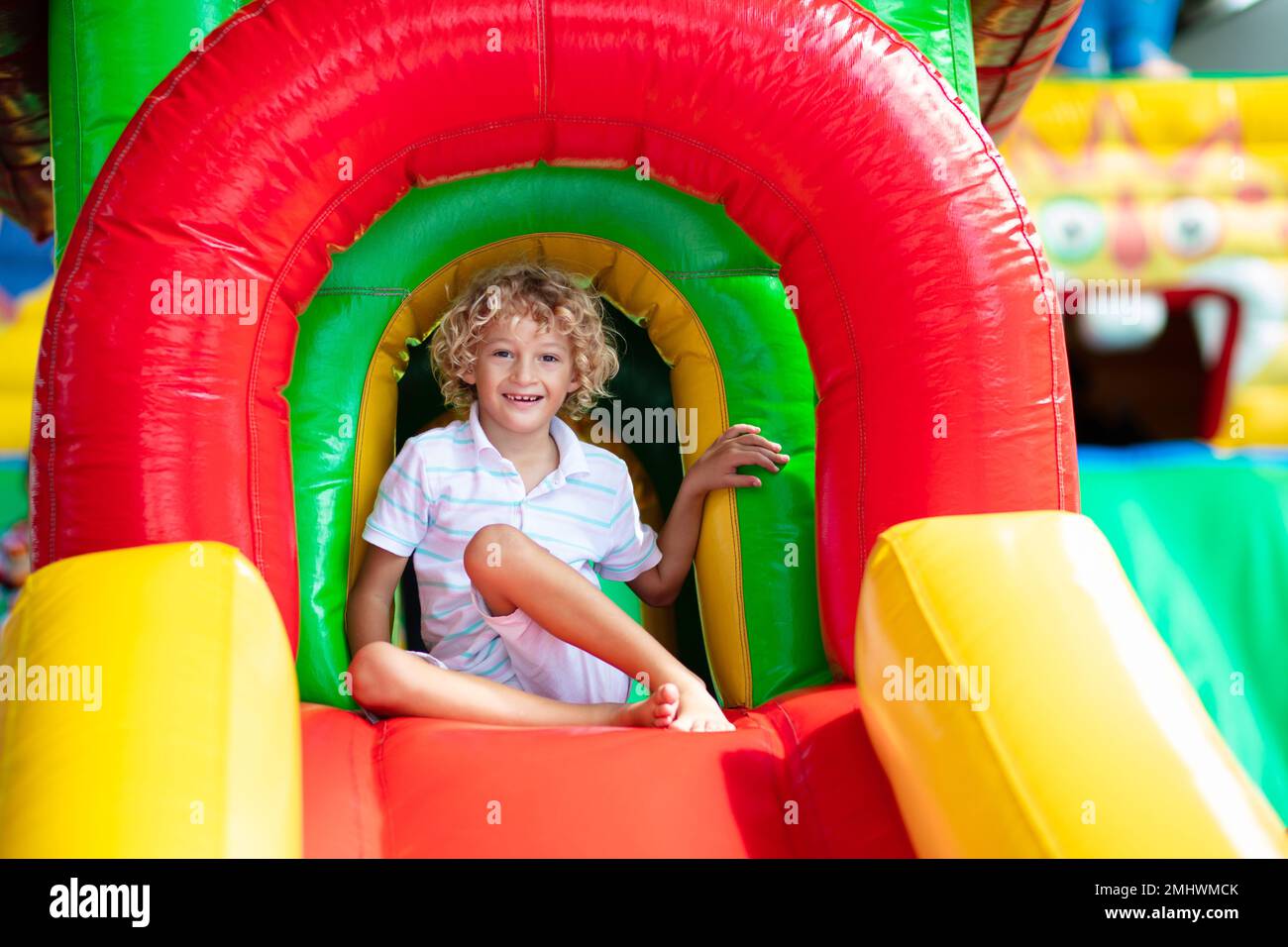 Child jumping on colorful playground trampoline. Kids jump in inflatable bounce castle on