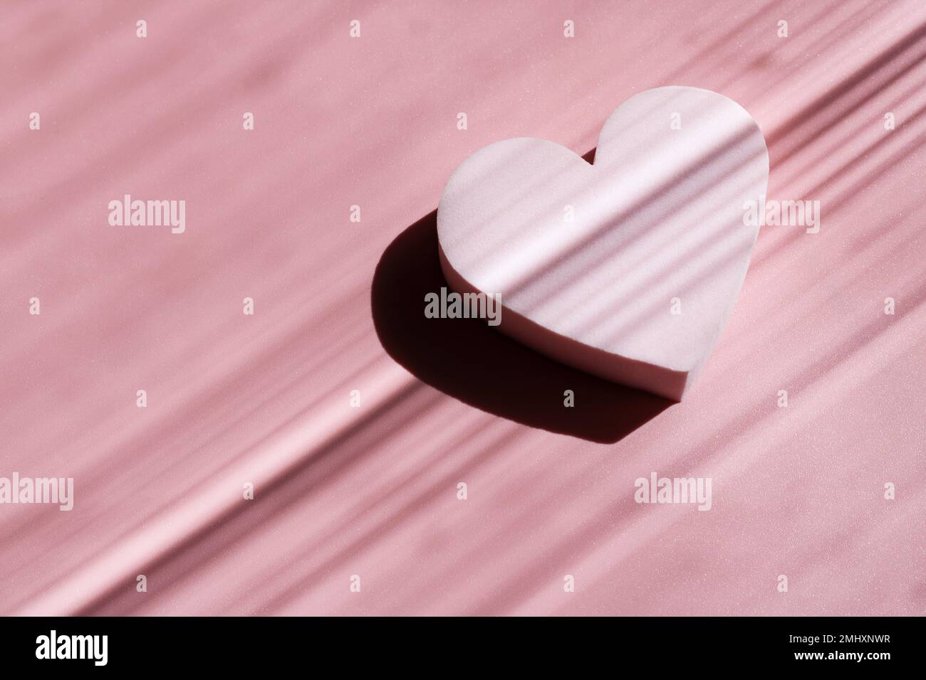 Pink powdery cosmetic sponge in the form of a star on a pink background with deep shadows. Beauty concept. Stock Photo