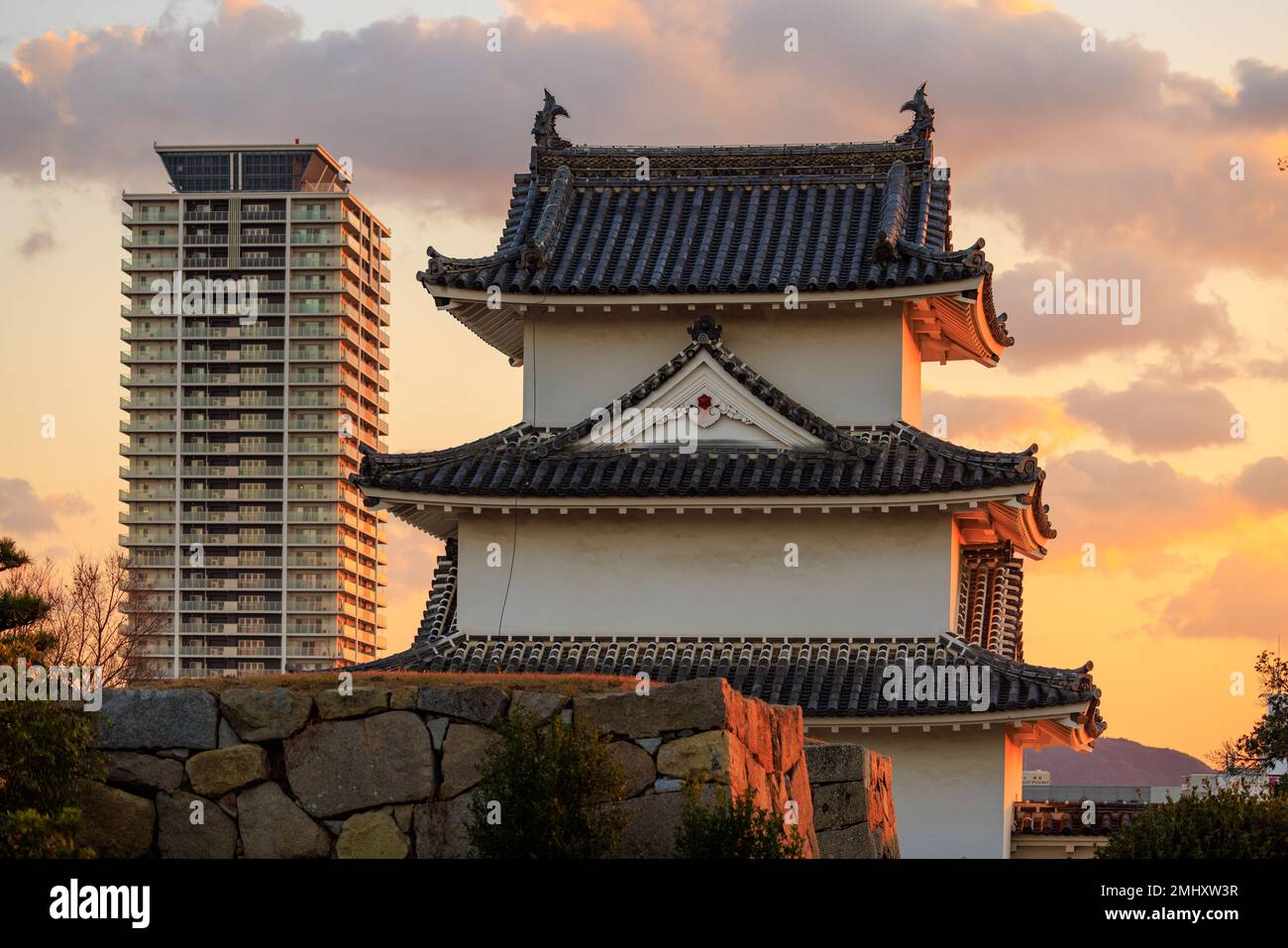 Sunset over watchtower in Japanese castle and modern high rise apartment building Stock Photo