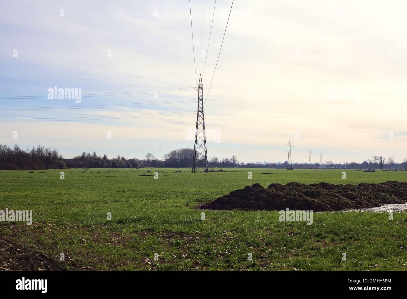 Cultivated field with electricity pylons and over head cables on a ...