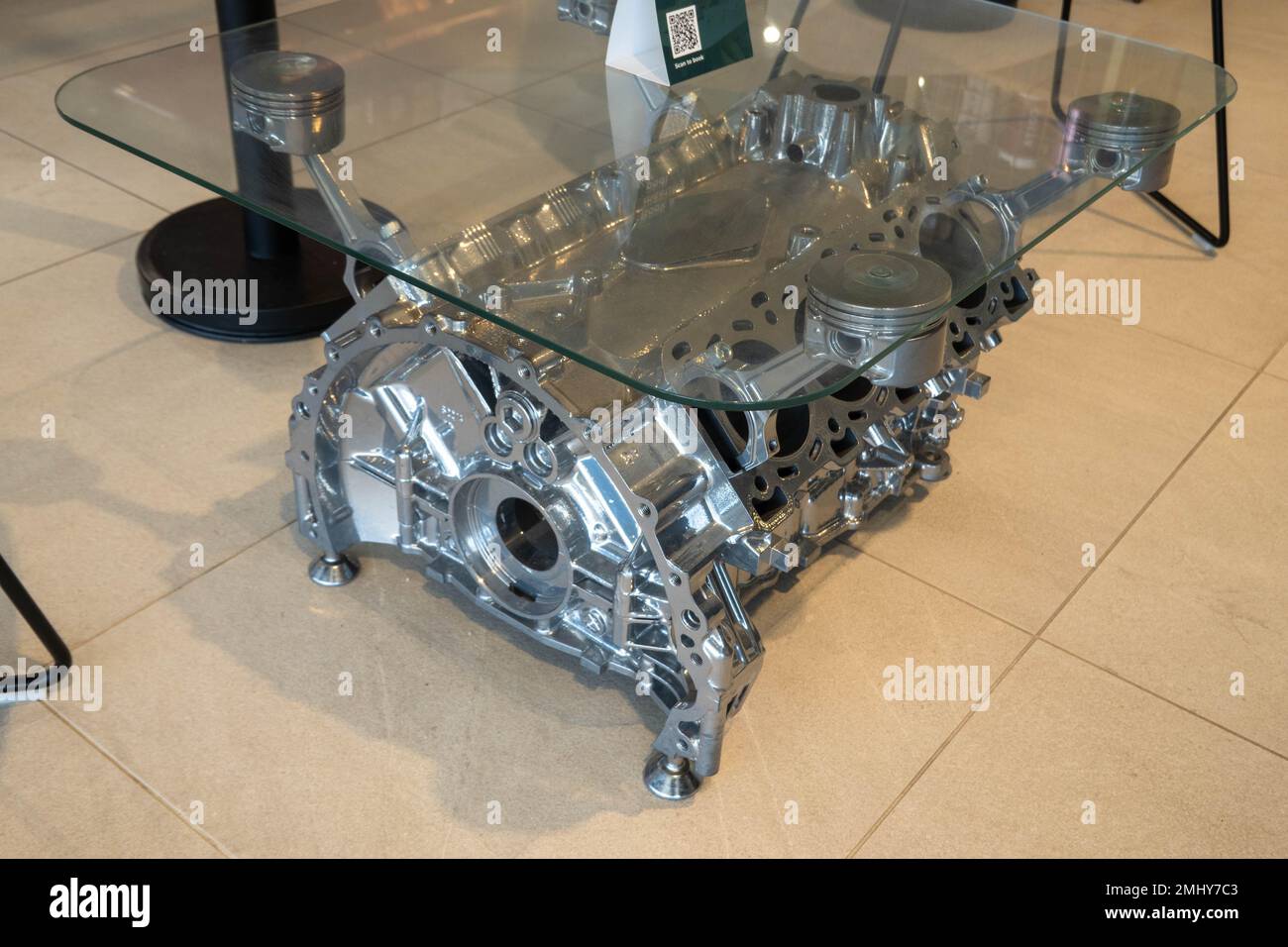 Engine block of a V8 being used as a coffee table with a glass top
