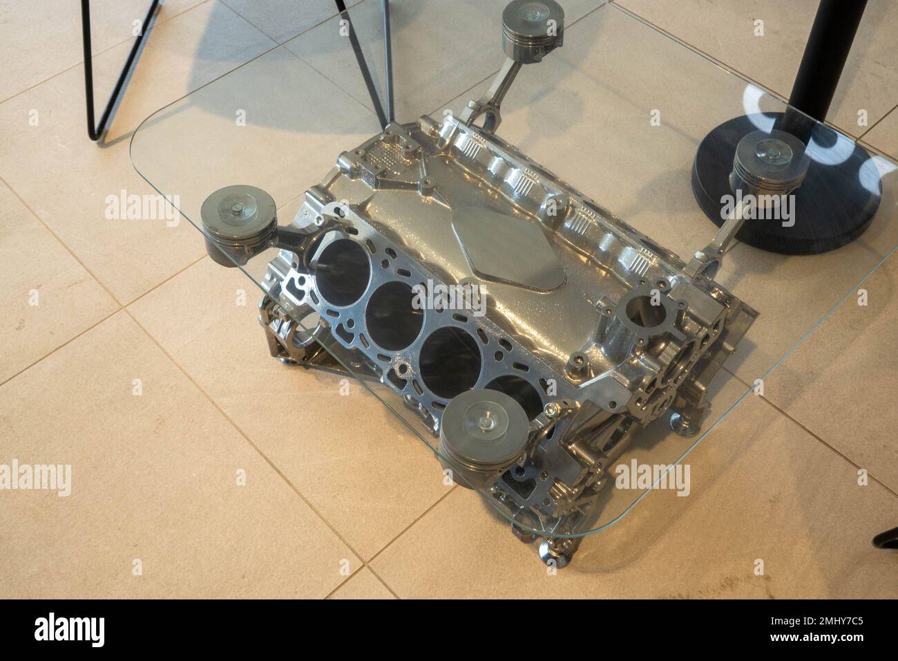 Engine block of a V8 being used as a coffee table with a glass top
