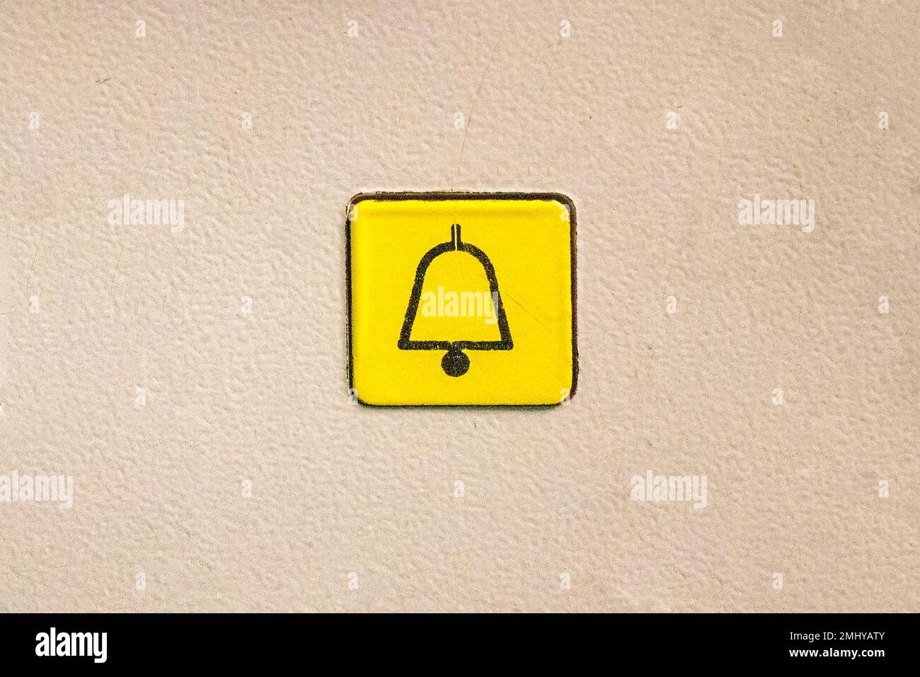 Single yellow square elevator button with a bell icon in a white background Stock Photo