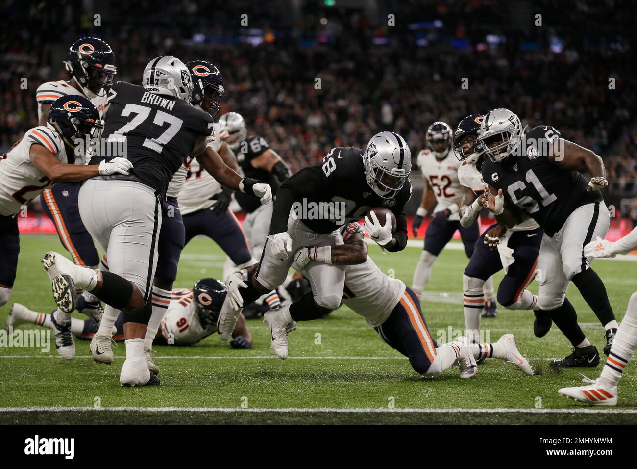 Oakland Raiders running back Josh Jacobs (28) breaks a tackle and goes in  for a touchdown during the first half of an NFL football game against the  Chicago Bears at Tottenham Hotspur
