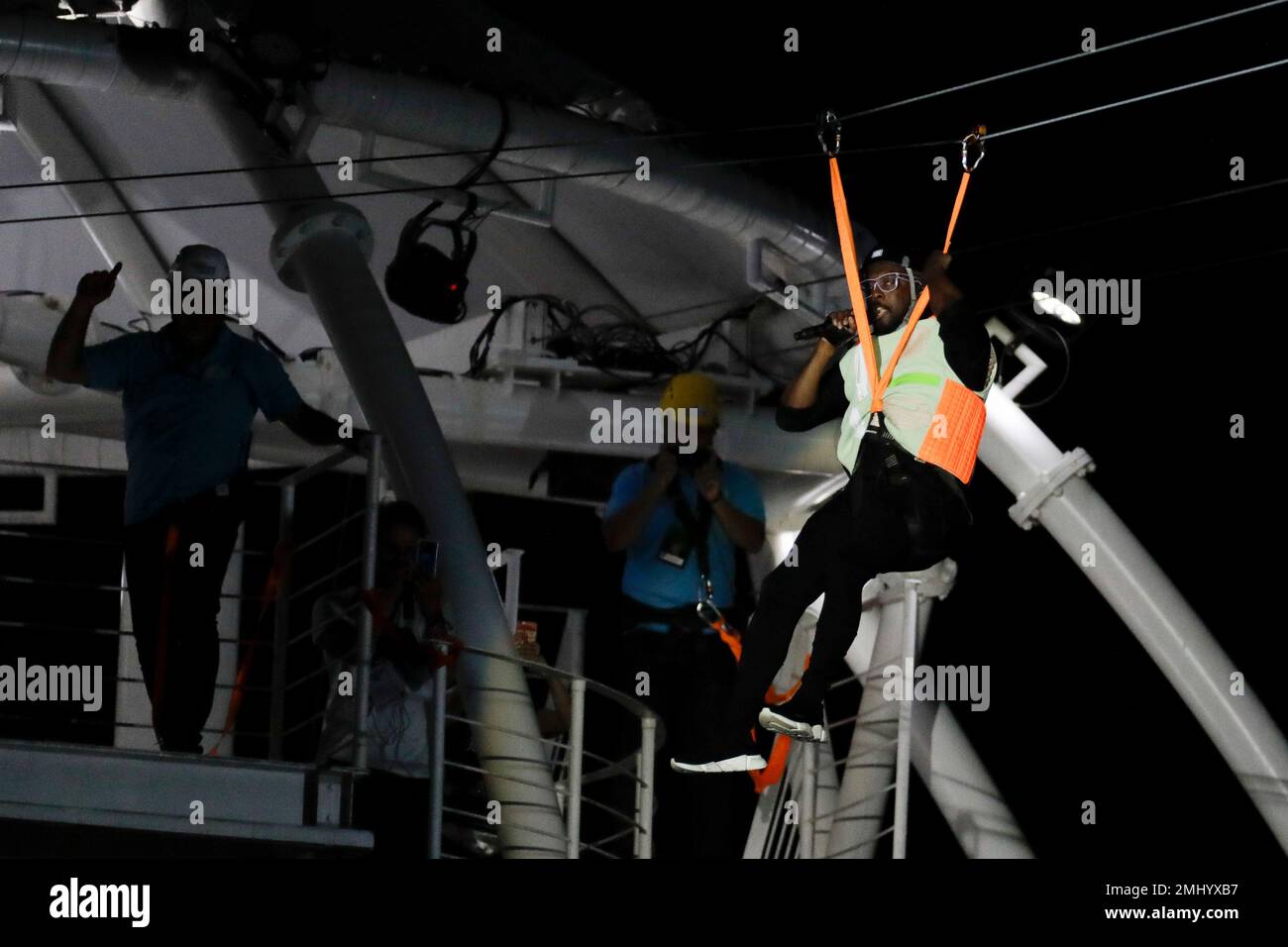 Will.i.am of the U.S. band Black Eyed Peas slides along a zip line as