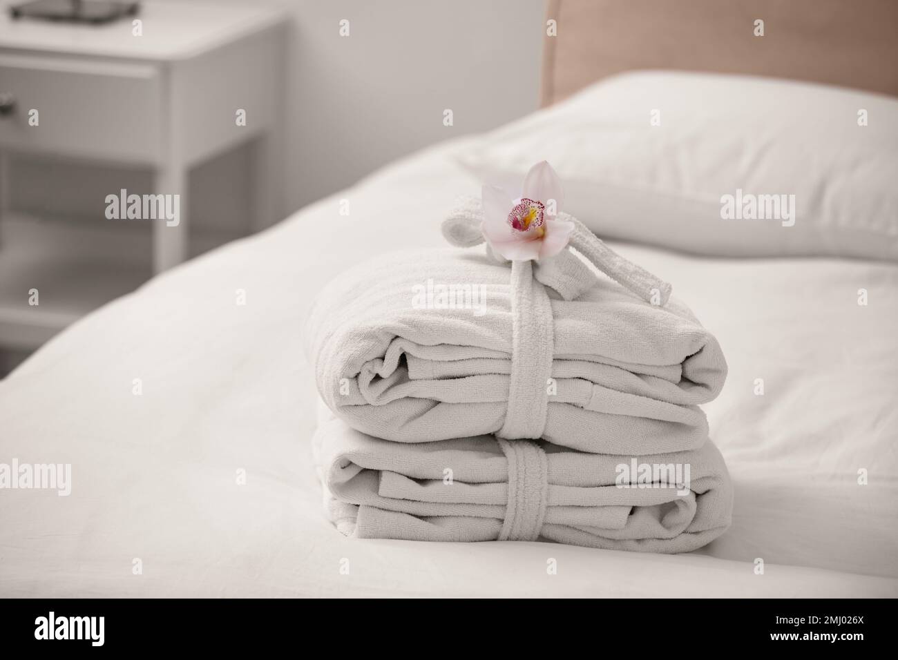 Clean folded bathrobes on bed in room Stock Photo Alamy