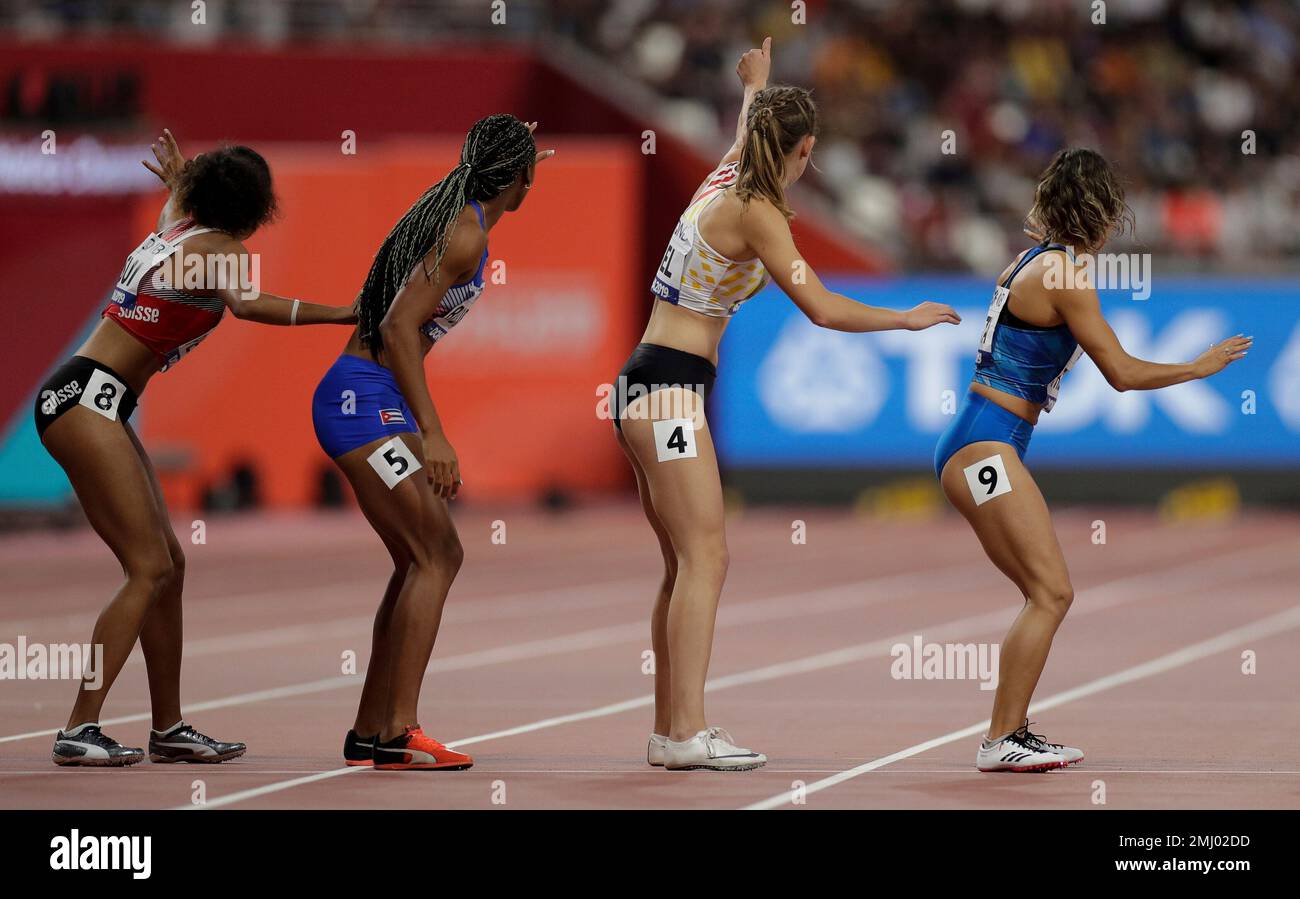 Runners wait for a baton changeover in a women's 4x400 meter relay heat