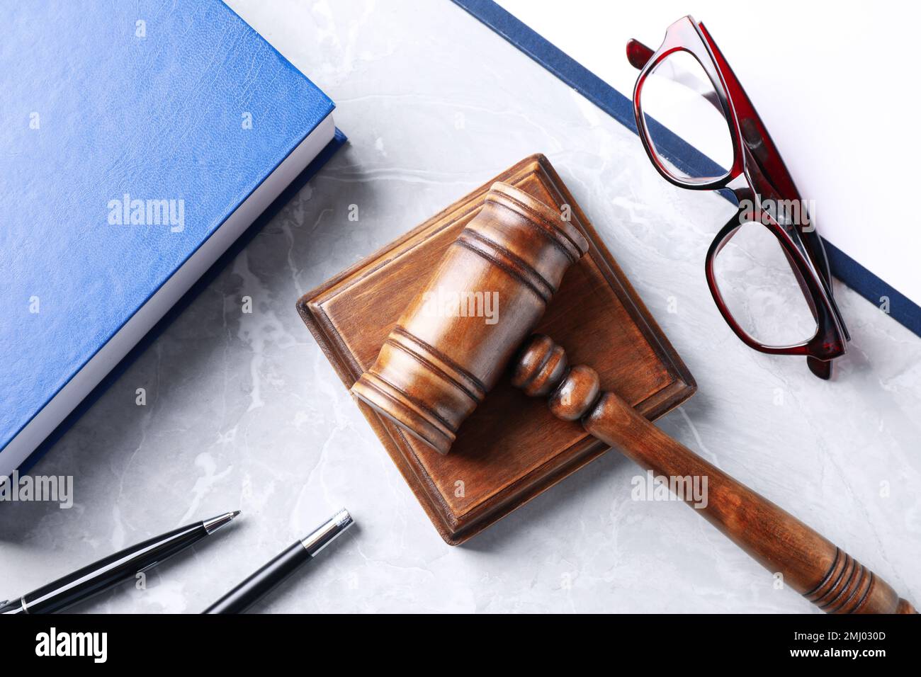 Flat lay composition with law book and gavel on light grey marble table