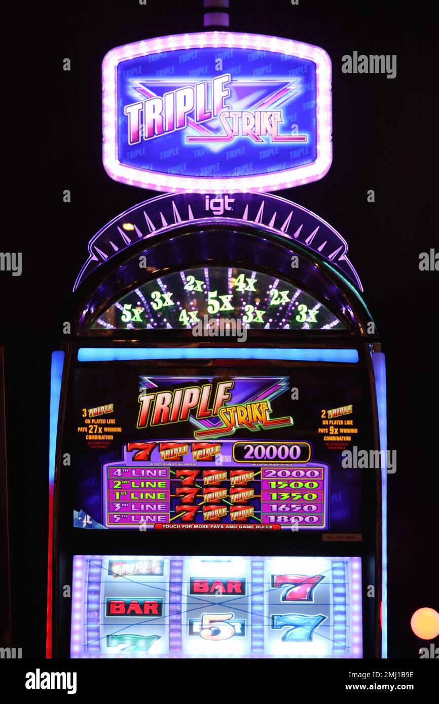 An illuminated slot machine with colourful graphics and flashing light sequences attract players by tempting them with the prospect of a quick reward. Stock Photo