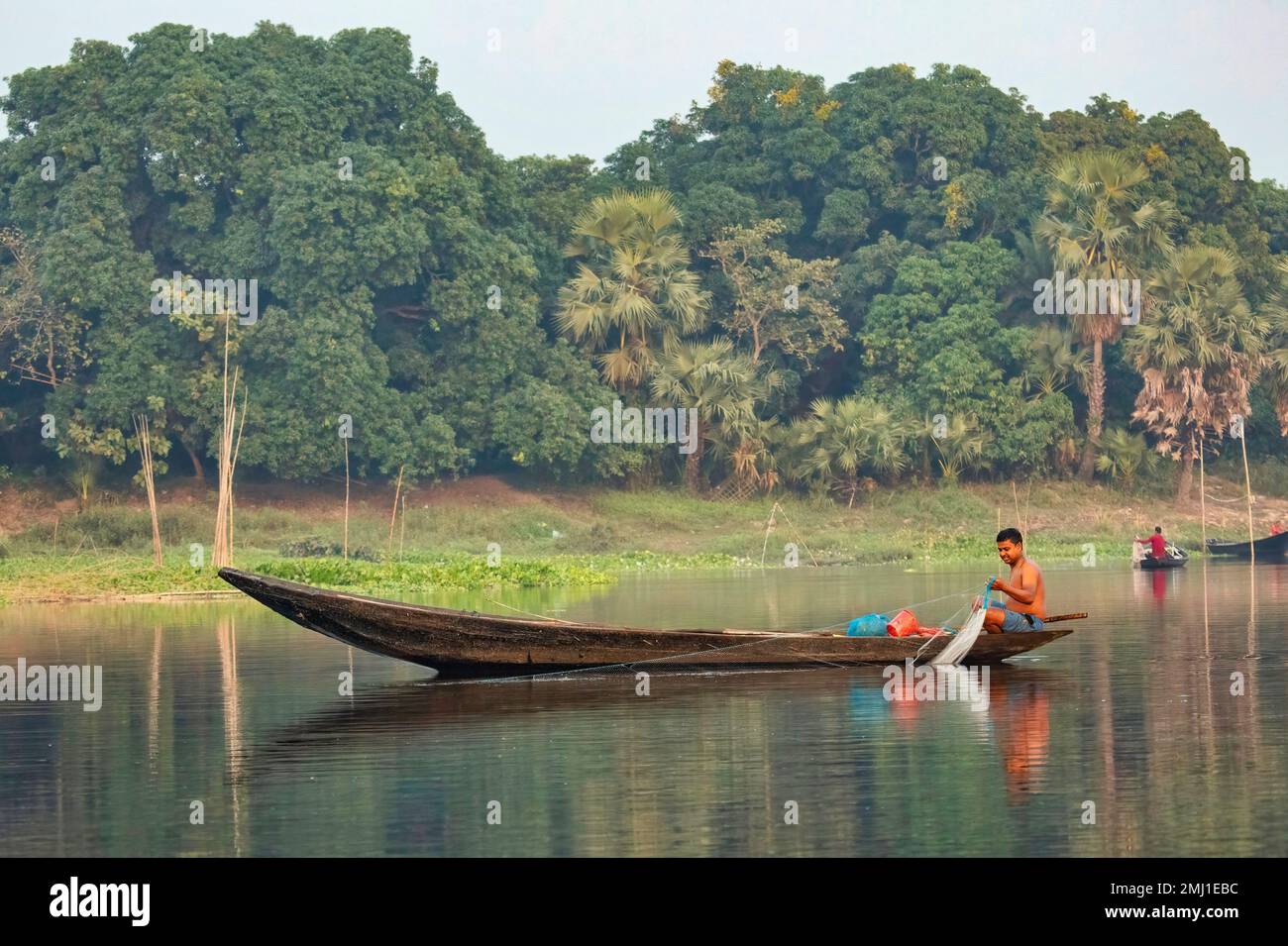 Man sitting on his boat fishing on river Ganges at in the estuary region of Purbasthali, Burdwan district, West Bengal, India Stock Photo