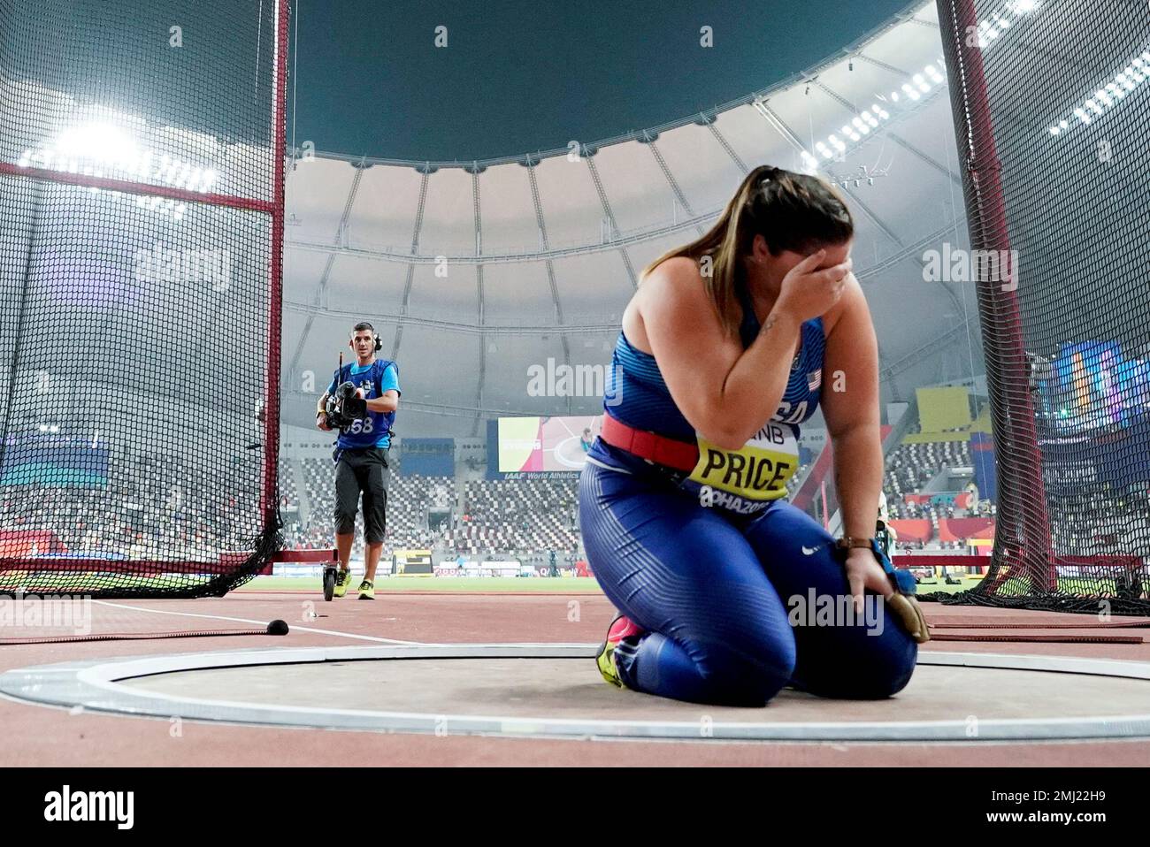 Deanna Price, of the United States, kneels at the throwing circle after winning the gold medal