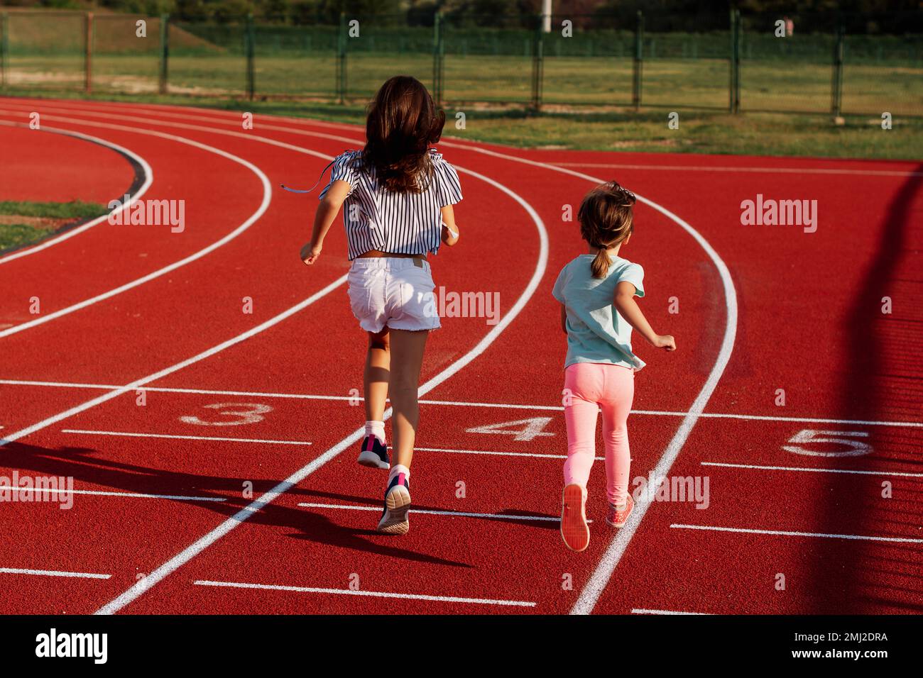 Two small girls running on outdoor track during summer day Stock Photo Alamy