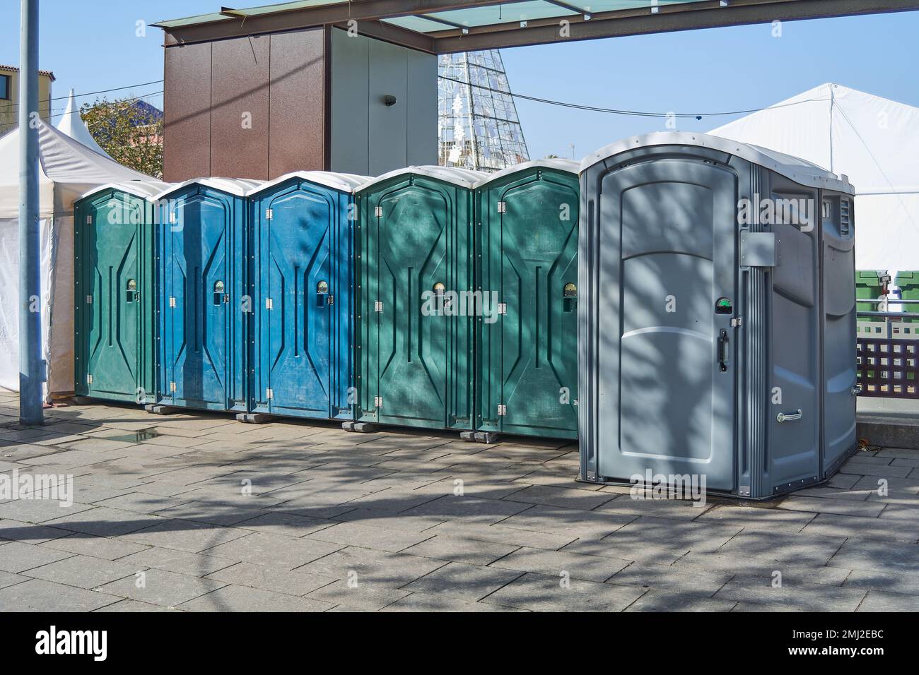 Six plastic toilet cabins of different colors. Public toilets in the town square. Stock Photo