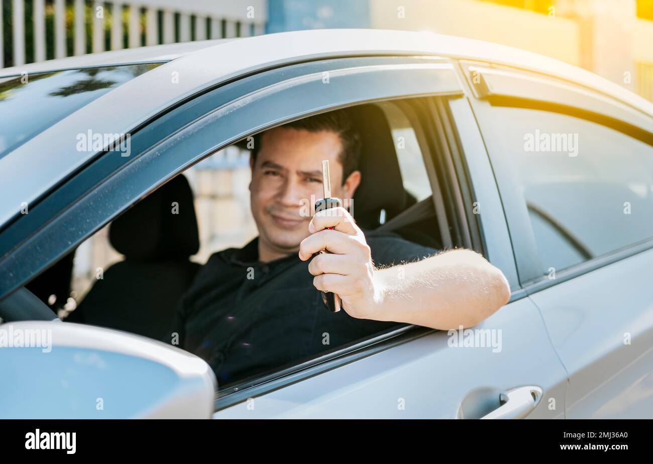 Happy man showing his new car keys, Person in his vehicle showing his car keys, Satisfied car buyer concept, Driver in his car showing the keys out Stock Photo