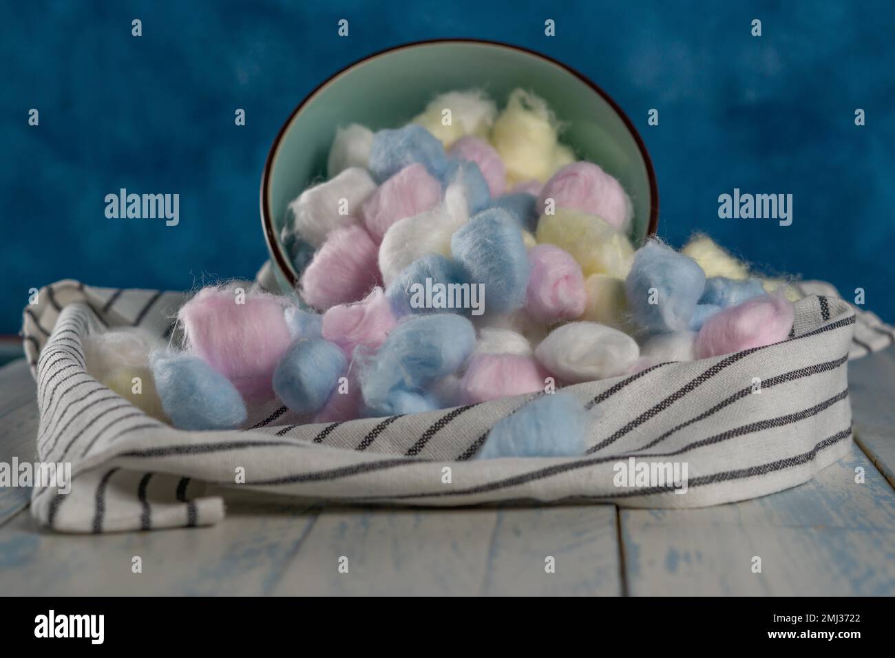Colored cotton balls in various containers on a blue background Stock