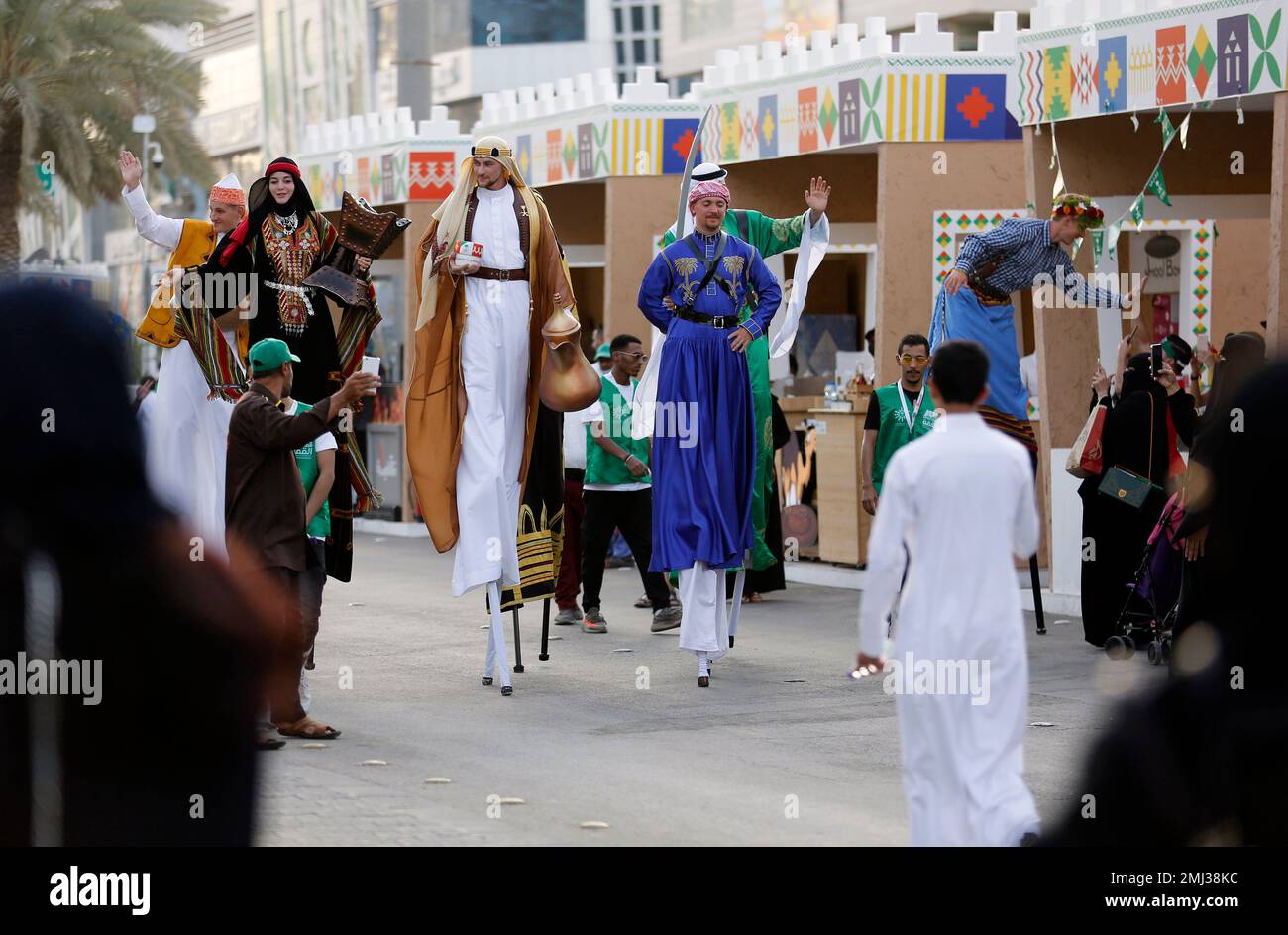 Dancers in traditional Saudi costumes perform on stilts marking