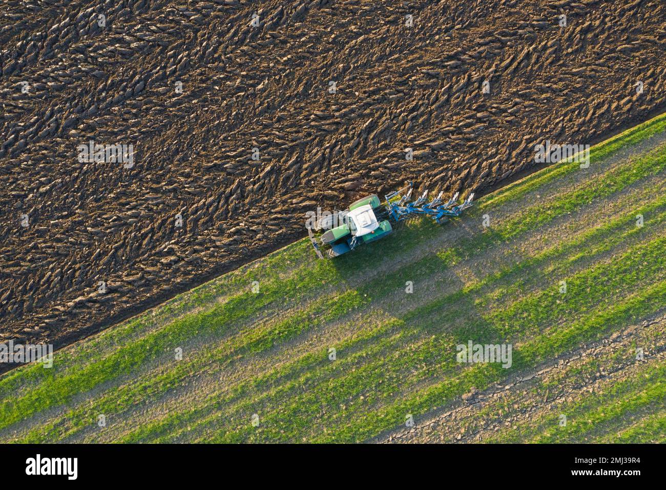 Tractor with plough, agricultural ploughing machine working on a field ...