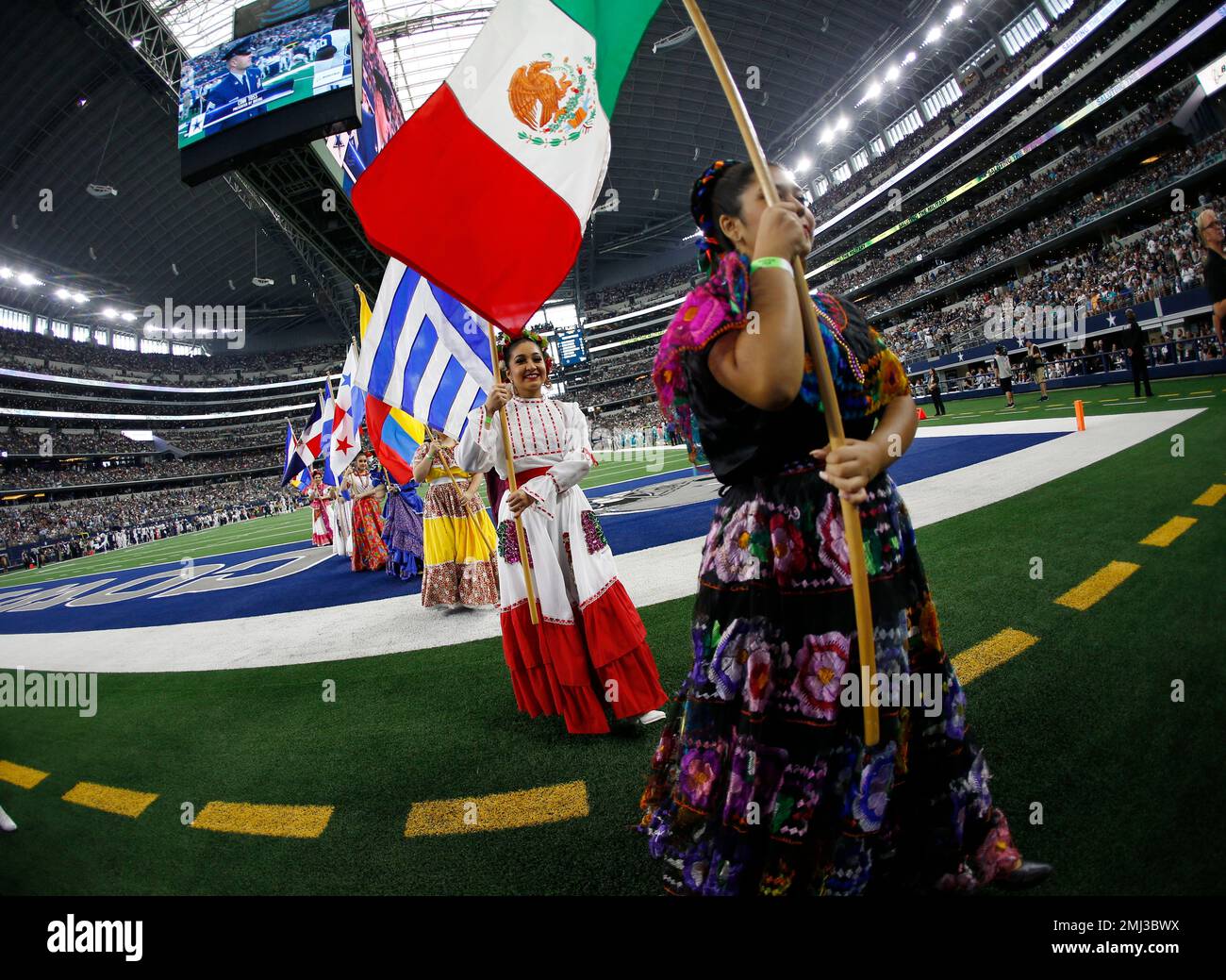 Dancers hold flags of nations of hispanic heritage honoring Hispanic  Heritage Month prior to a NFL football game between the Miami Dolphins and  Dallas Cowboys in Arlington, Texas, Sunday, Sept. 22, 2019. (