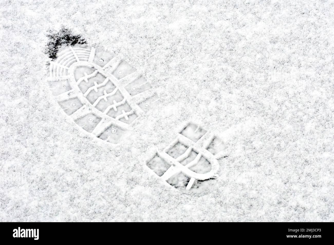 Close up of a bootprint made in a thin layer of freshly fallen snow ...