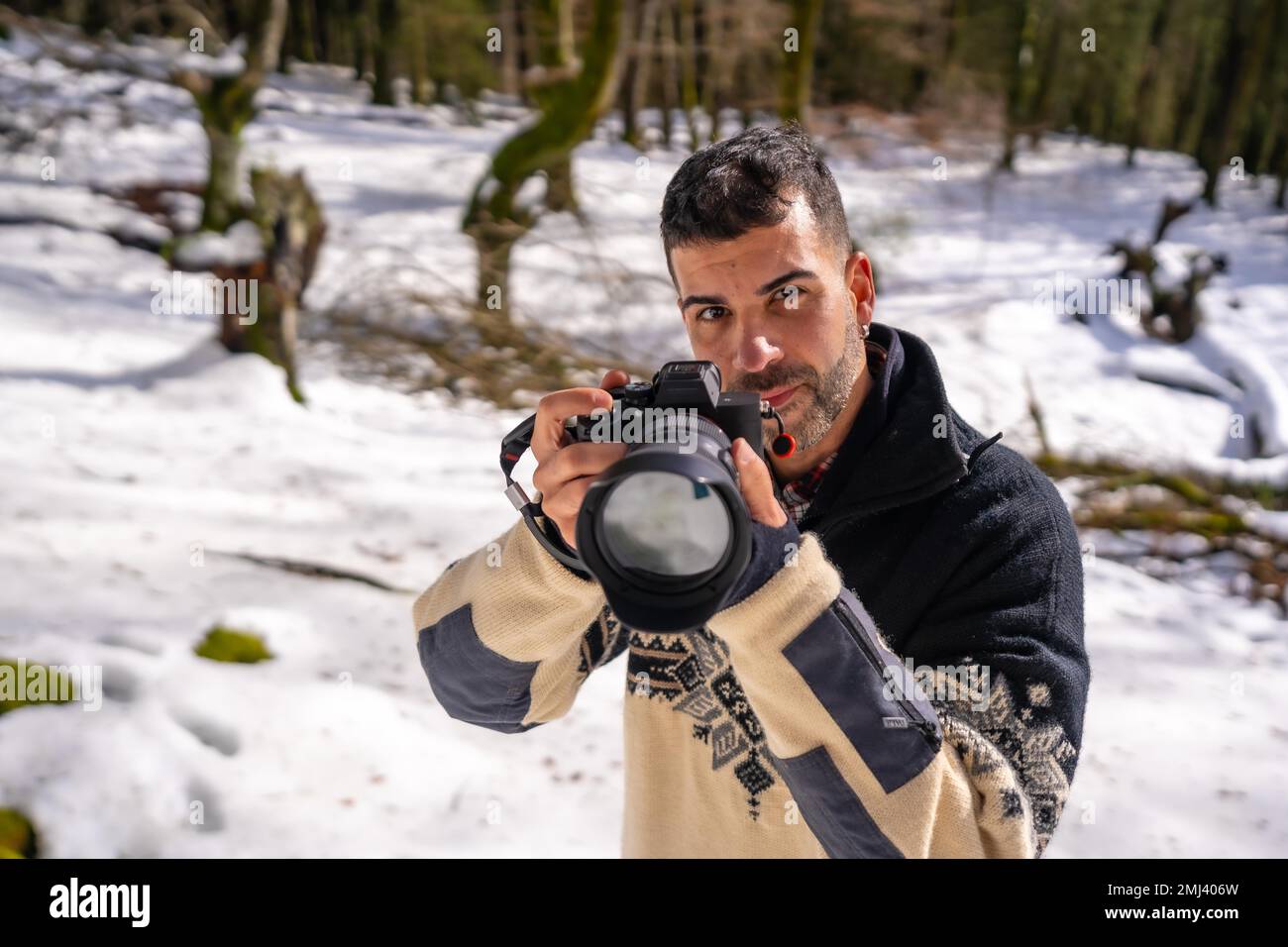 Photographer man taking a photo in the snow, enjoying winter photography in a snowy forest Stock Photo
