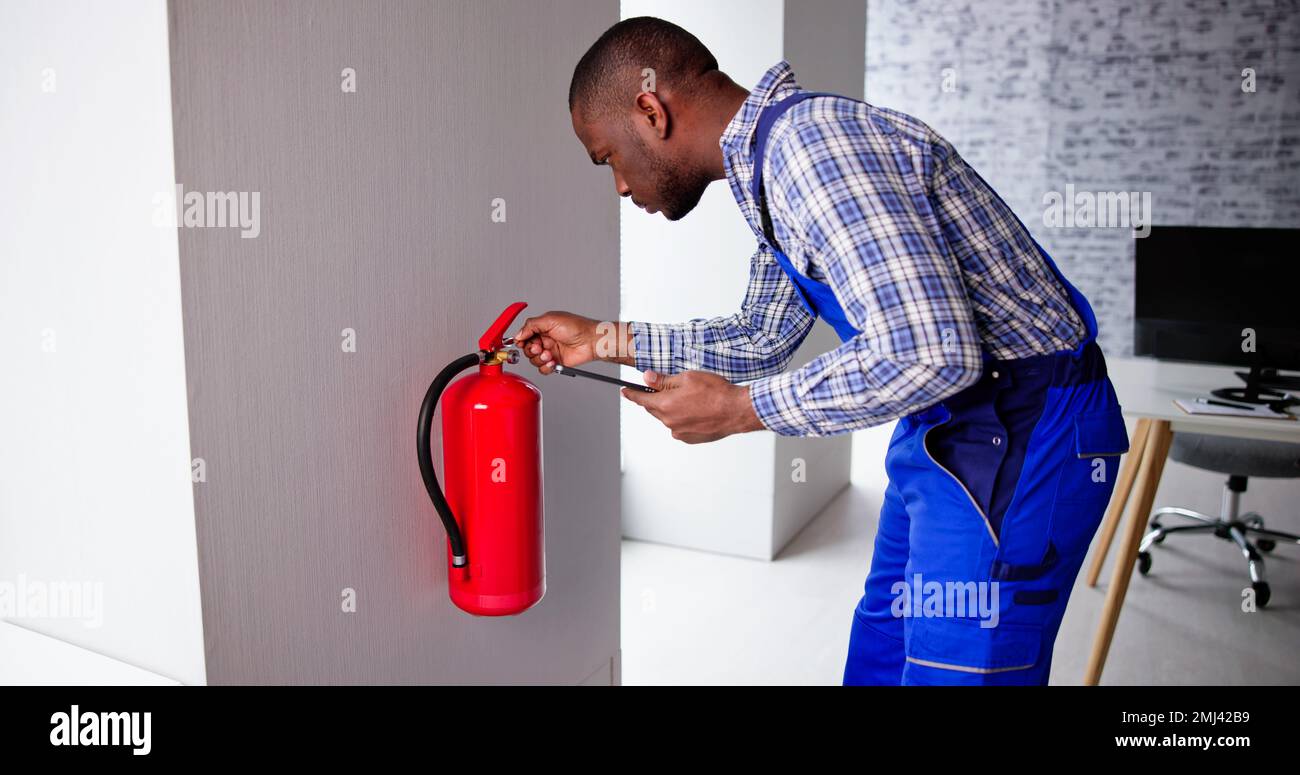 Male Professional Checking A Fire Extinguisher Security Inspection Stock Photo