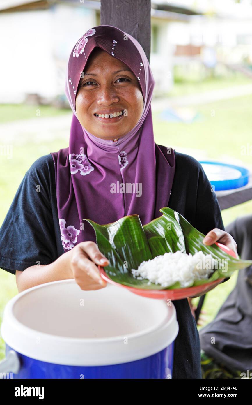 Malaysian woman with headscarf showing rice in banana leaf, Abai Village, Kinabatangan District, Sabah, Borneo, Malaysia Stock Photo