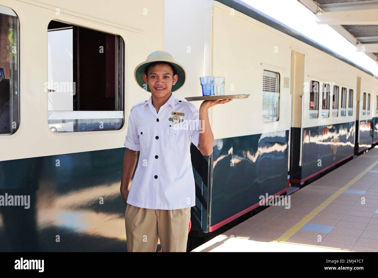 Steward in work uniform of North Borneo Railway serving drinks, Kota Kinabalu, Sabah, Malaysia Stock Photo
