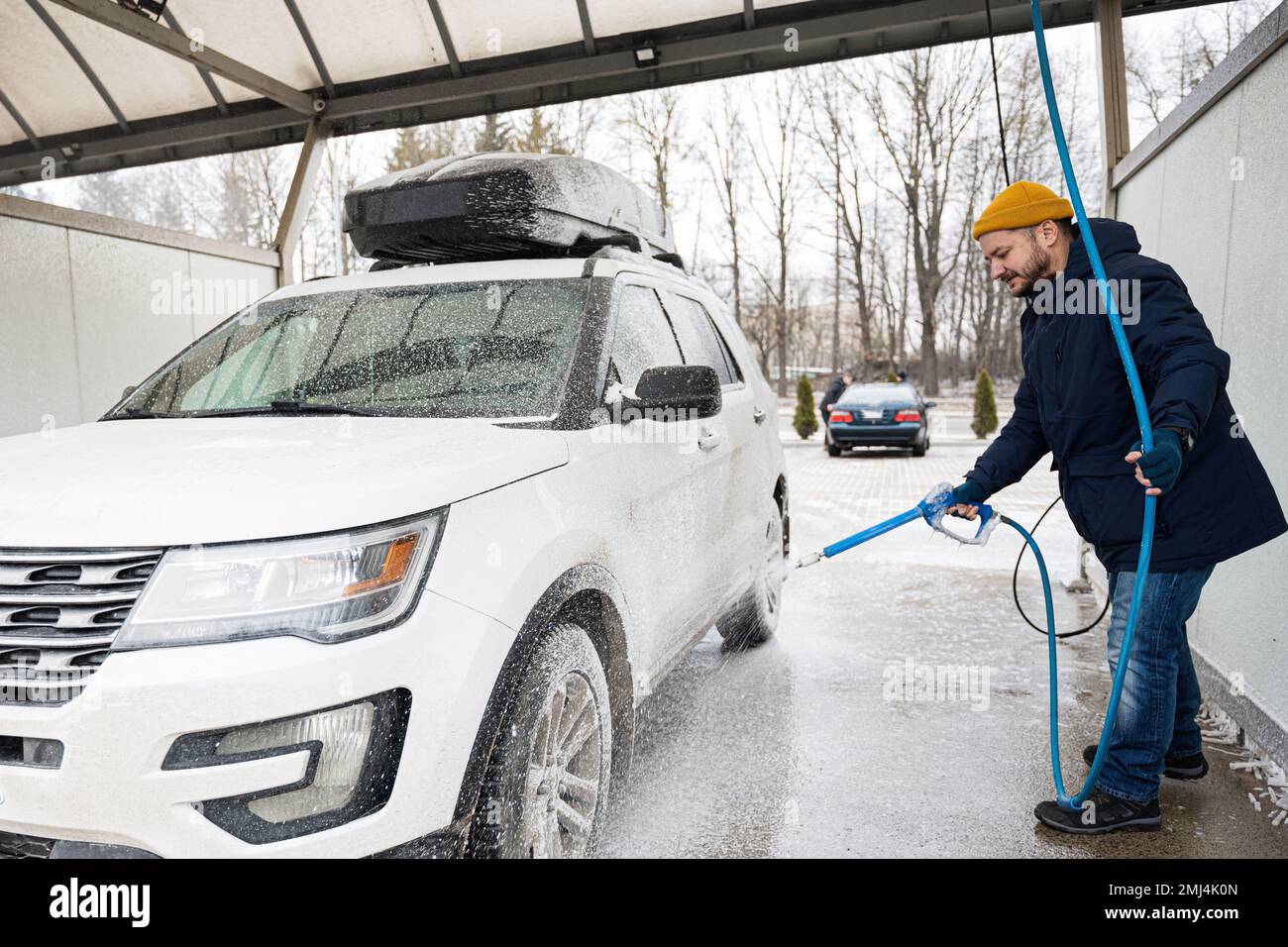 Man washing american SUV car with roof rack at a self service wash in cold weather Stock Photo