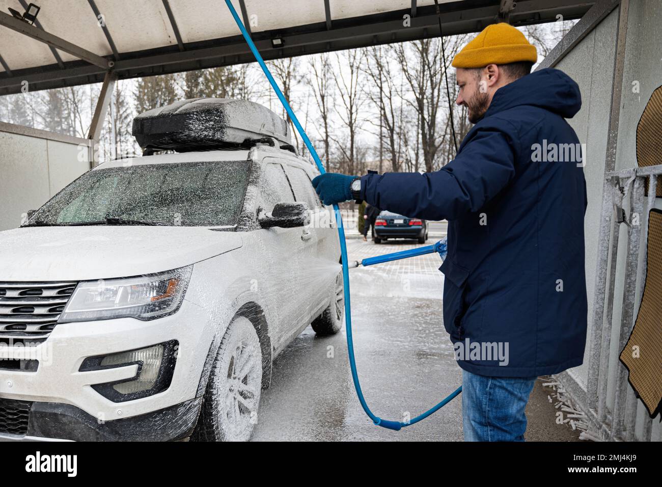 Man washing american SUV car with roof rack at a self service wash in