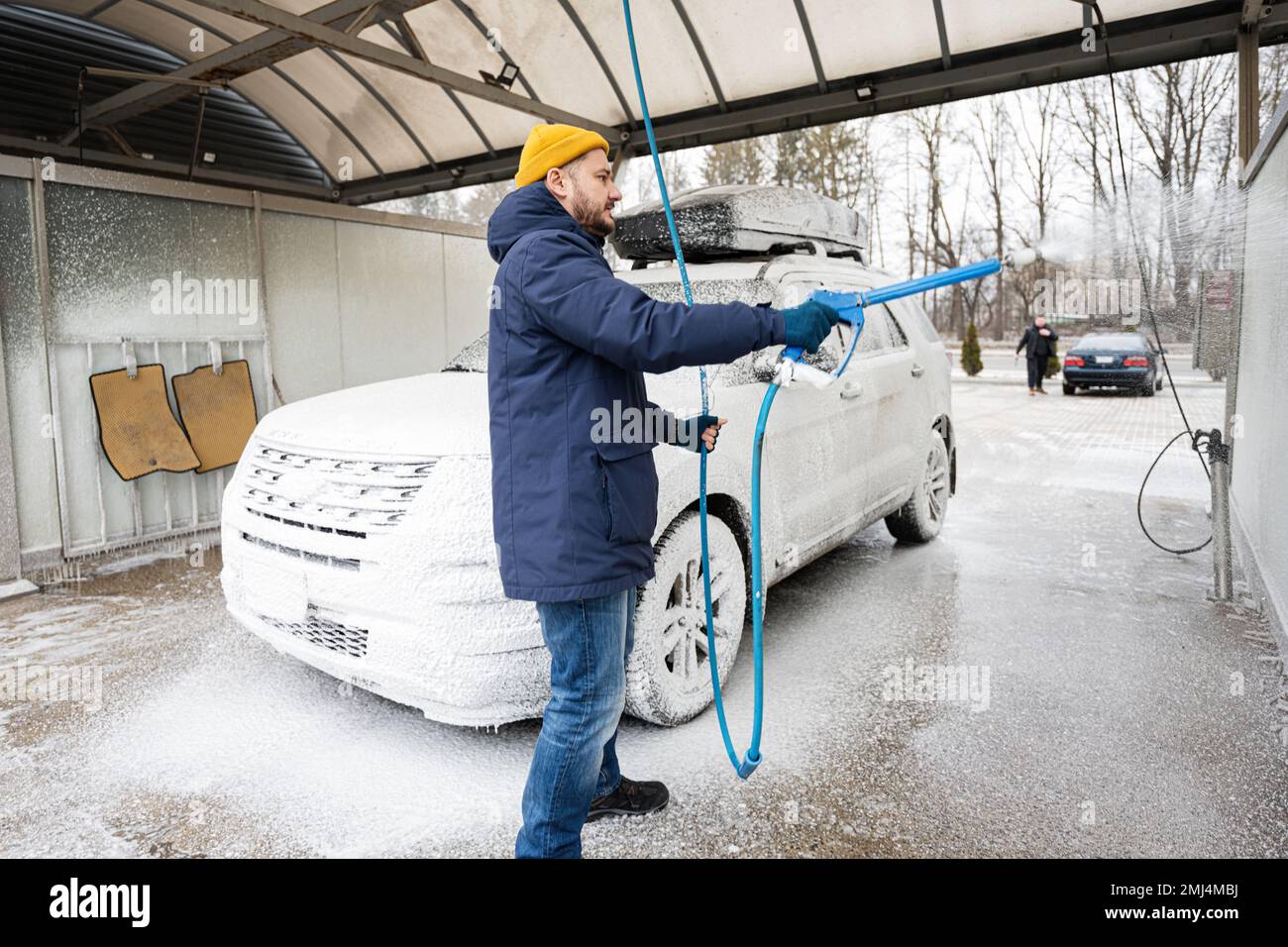 Man washing american SUV car with roof rack at a self service wash in cold weather Stock Photo