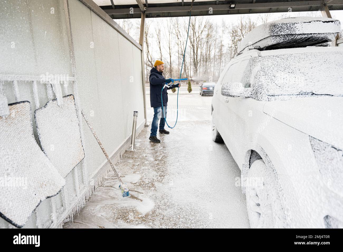 Man washing american SUV car with roof rack at a self service wash in