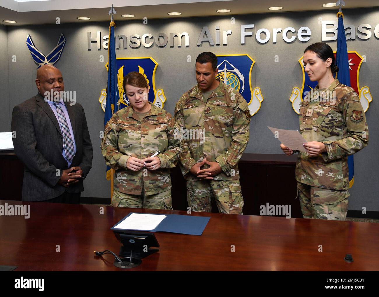 Col. Taona Enriquez, second from left, installation commander, prepares to sign a Women’s Equality Day proclamation at Hanscom Air Force Base, Mass., Aug. 25, while James Clarke, from left, Hanscom’s Diversity, Equity, Inclusion and Accessibility employment manager, Chief Master Sgt. Alan Weary, installation command chief, and Tech. Sgt. Katsiaryna Durant, WED Committee member, look on. Women's Equality Day commemorates the ratification of the 19th Amendment to the U.S. Constitution that granted women the right to vote. Stock Photo