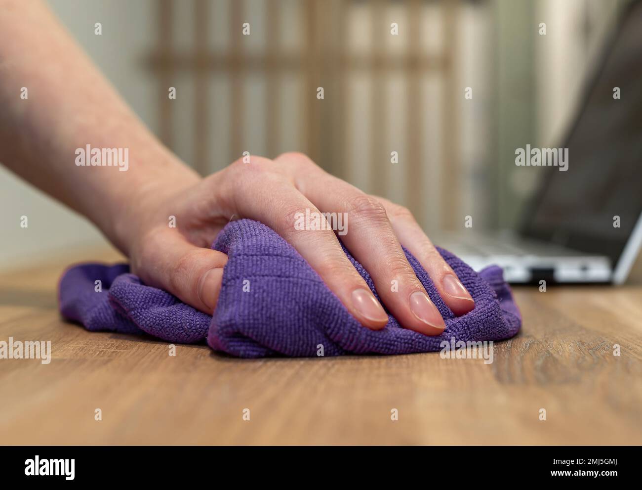 Hand with cloth, wiper, cleaning wood table surface from dust